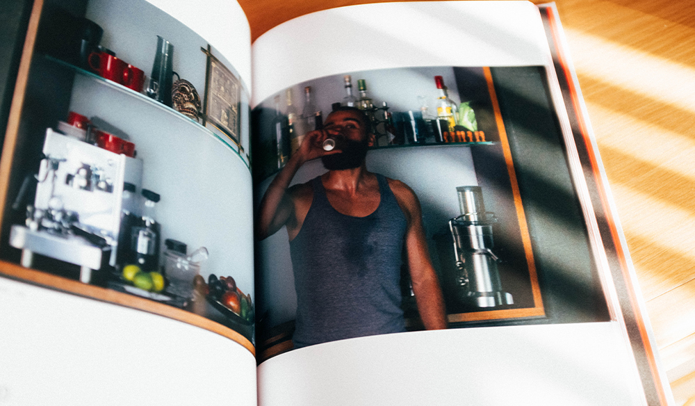 Image of a man drinking from the Ex Machina screenplay book. 