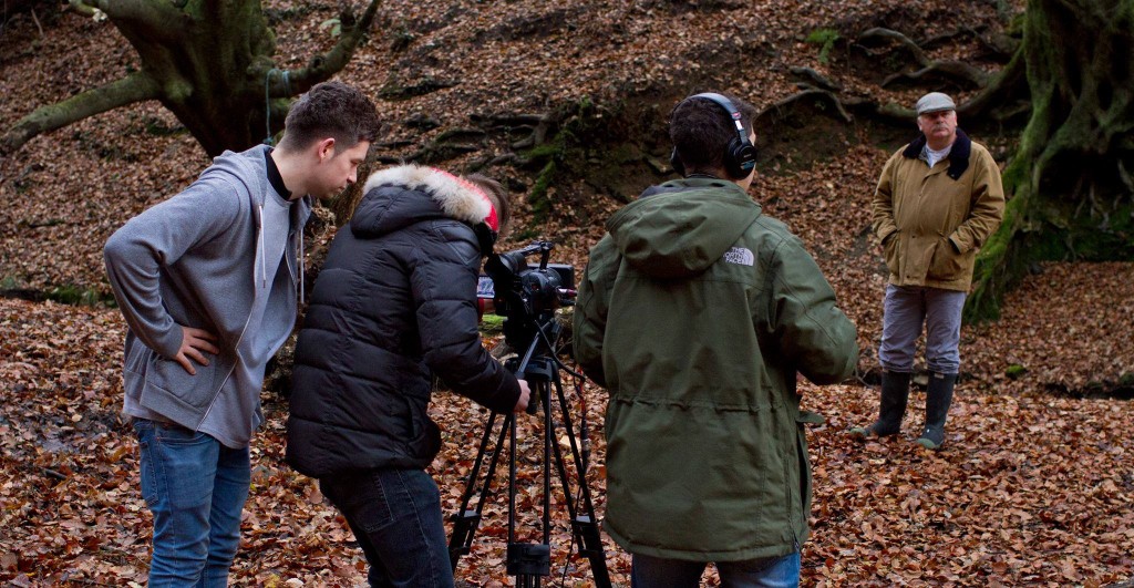 Image of a small film crew filming an actor in the forest. 