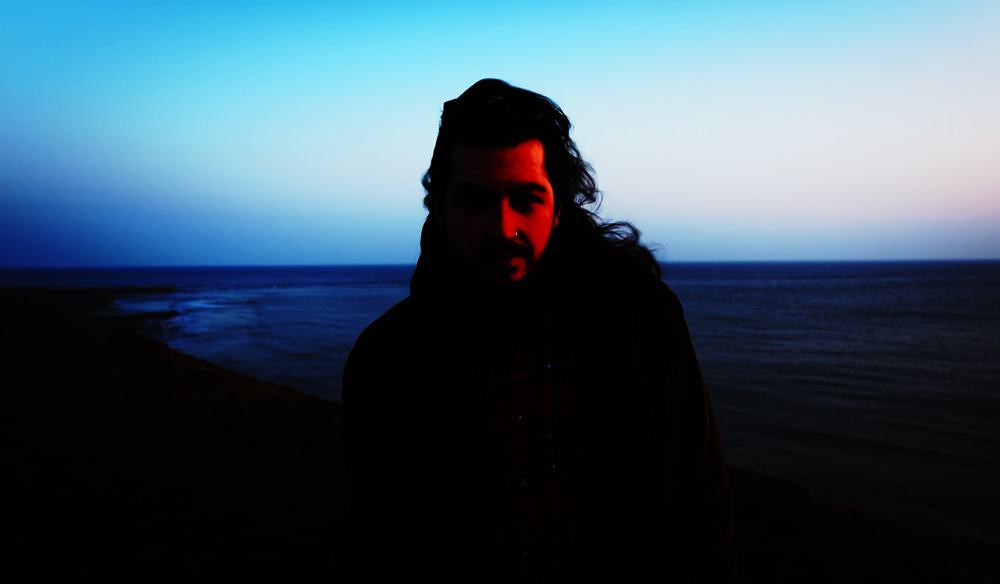 Contrasted image of a man standing by the coast