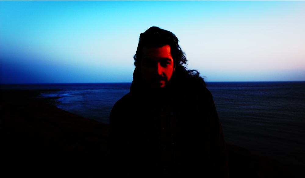 Image of a man by the coast with heavy contrast applied. 