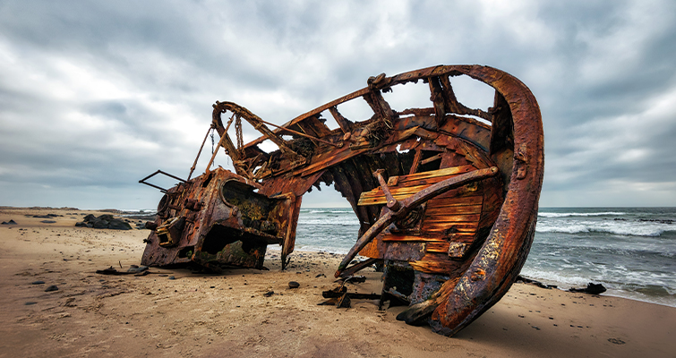Picture of a rusty shipwreck on a beach at daytime. 