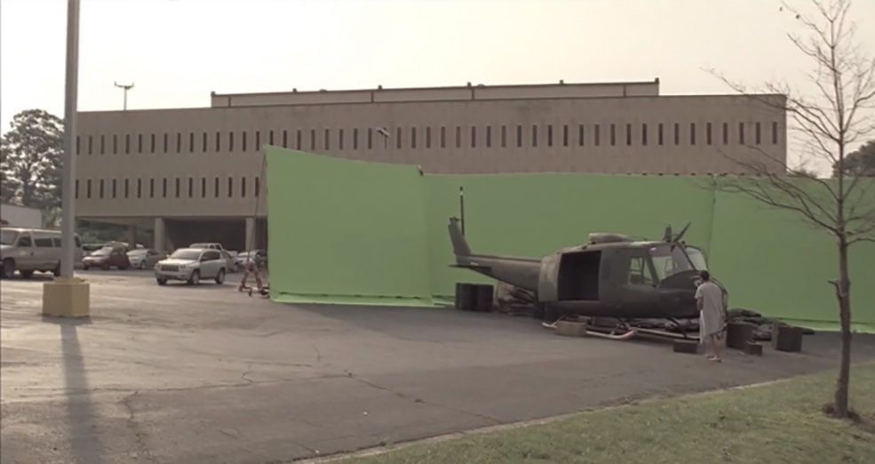 Picture of an outdoor film loaction with a large greenscreen and a wreckage of a helicopter in front. 