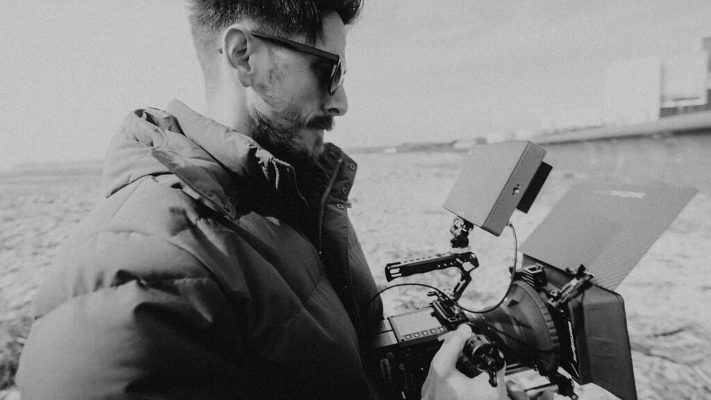 Man with sunglasses outdoors looking at the external monitor screen on the RED KOMODO 